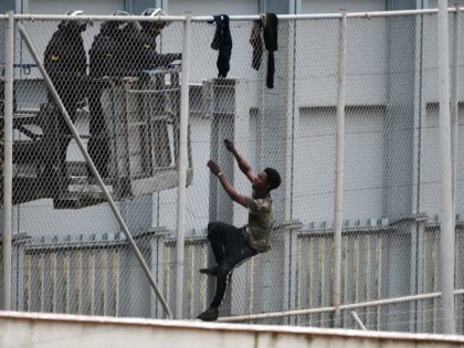 A youth tries to climb over the border fence in the Spanish exclave of Ceuta bordering Morocco on April 13, 2021. - Melilla and Ceuta, another Spanish territory in North Africa, have the European Union's only land borders with Africa, making then popular entry points for migrants seeking a better …