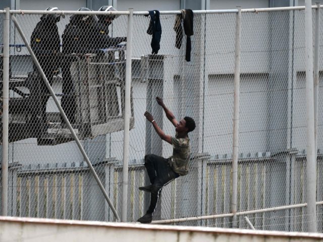 A youth tries to climb over the border fence in the Spanish exclave of Ceuta bordering Mor