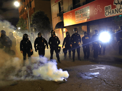 Police officers stand behind a canister of tear gas during a protest sparked by the death