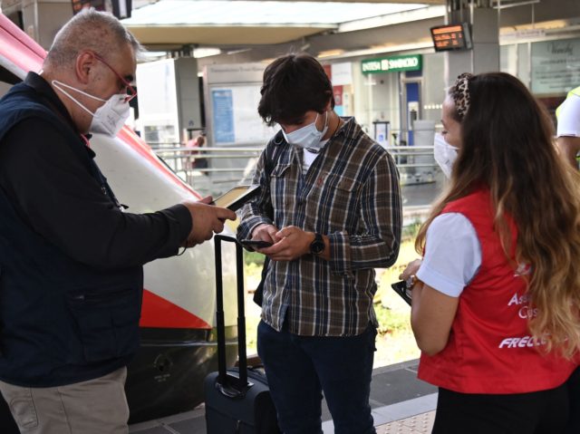 An inspector (L) checks passengers boarding a high-speed "Frecciarossa" train for their so