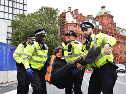 A climate activist from the group Insulate Britain is arrested and carried away by police during a demonstration in which they blocked a round about calling for the UK government to fund the insulation of Britain's homes in central London on October 8, 2021. - Climate activist group Insulate Britain …