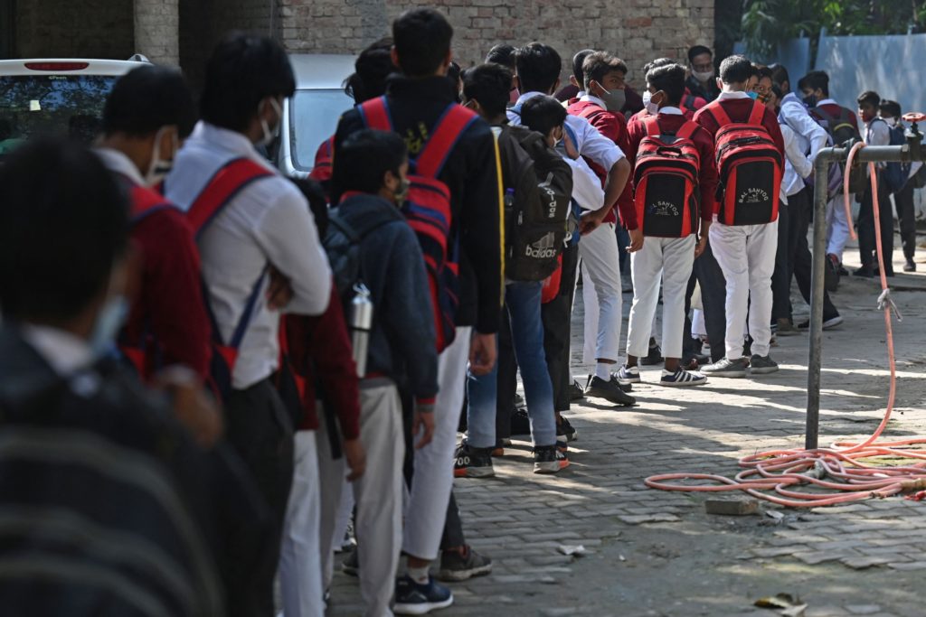Students stand in a queue to enter their school in New Delhi on November 29, 2021, as educational institutions were reopened after the air quality levels in the city showed improvement. (Photo by Money SHARMA / AFP) (Photo by MONEY SHARMA/AFP via Getty Images)