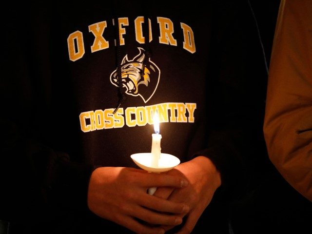 A student holds a candle during a vigil after a shooting at Oxford High School at Lake Poi