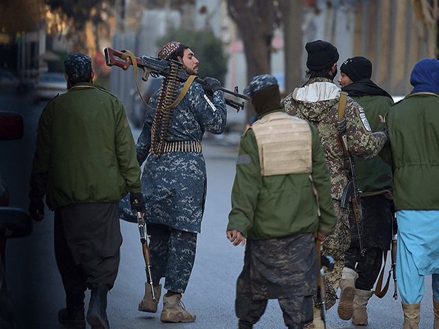 Taliban fighters walk along a roadside at Shahr-e Naw neighbourhood in Kabul on December 9