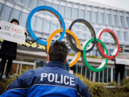 A policeman talks with Tibetan activists from the Students for a Free Tibet association as they protest in front of the International Olympic Committee (IOC) headquarters ahead of the February's Beijing 2022 Winter Olympics, on December 11, 2021 in Lausanne. - Human rights campaigners and exiles accuses Beijing of religious …