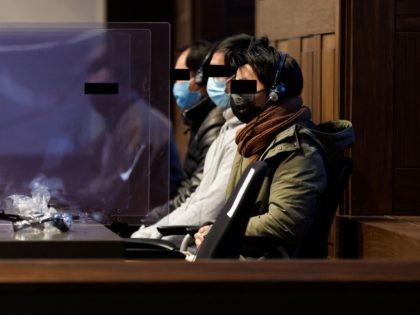 Defendants sit in a box at the opening of the trial of 23 people suspected of involvement in a human-smuggling ring, on December 15, 2021 in Bruges, two years after 39 Vietnamese migrants died aboard a refrigerated truck that travelled to Britain. - The Bruges trial will focus on the …