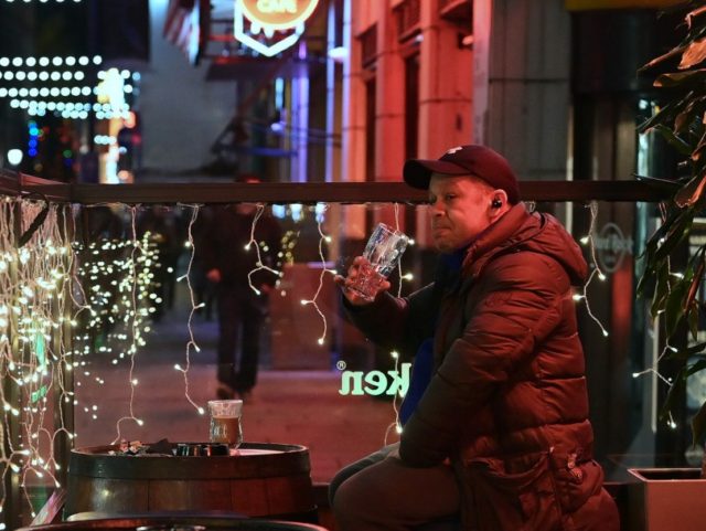 DUBLIN, IRELAND - DECEMBER 20: A customer finishes his drink outside after bars in the Tem