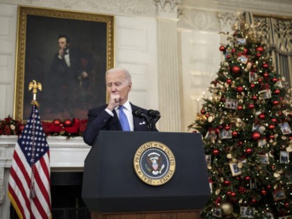 WASHINGTON, DC - DECEMBER 21: U.S. President Joe Biden coughs while speaking about the omicron variant of the coronavirus in the State Dining Room of the White House, December 21, 2021 in Washington, DC. As the omicron variant fuels a new wave of COVID-19 infections, Biden announced plans that will …