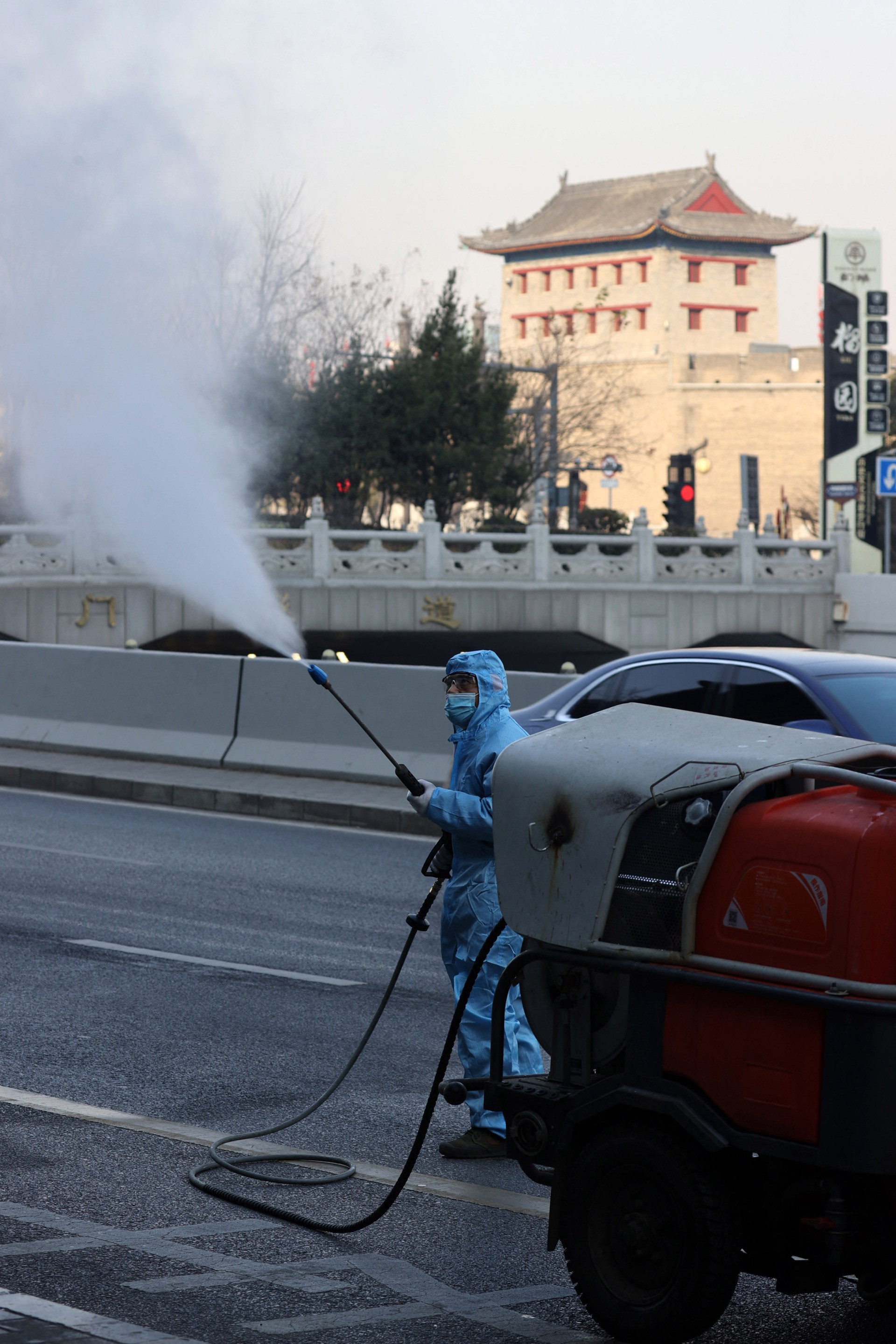 This photo taken on December 22, 2021 shows a staff member spraying disinfectant on street in Xi'an in China's northern Shaanxi province. - China OUT (Photo by AFP) / China OUT (Photo by STR/AFP via Getty Images)