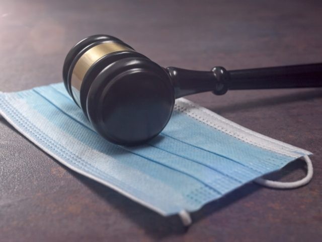 Close-up of a Judge Gavel Resting On A Protective Mask.