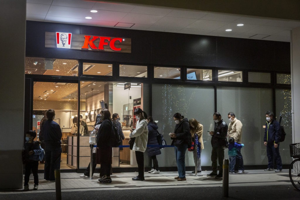 People queue in front of a KFC restaurant on December 23, 2020 in Tokyo, Japan. KFC at Christmas has become something of a tradition in Japan with some attributing its yuletide popularity to a kindergarten delivery being made in a Santa Claus outfit which was such a success it was requested by a number of other schools and subsequently gave the company the idea of associating its product to Christmas. The chain launched its first Christmas campaign in December 1974, and has continued to do so every year at all its outlets nationwide. In 2018, KFC Japan posted all-time high sales of roughly 68 million USD for the five days from December 21 to 25. Roughly 10 percent of its annual turnover for the entire year. (Photo by Yuichi Yamazaki/Getty Images)