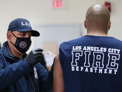 A Los Angeles Fire Department (LAFD) firefighter receives a Moderna COVID-19 vaccination dose from firefighter Michael Perez (L) at a fire station on January 29, 2021 in Los Angeles, California. LAFD has recorded a ‘sharp decline’ in coronavirus cases after firefighters began receiving the vaccine shots on December 28. (Photo …