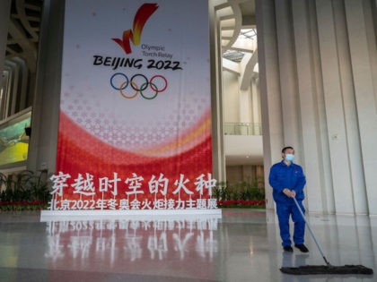 BEIJING, CHINA - DECEMBER 19: A worker sweeps near a display of the Olympic Flame for the Beijing 2022 Winter Olympics at the Olympic Tower on December 19, 2021 in Beijing, China. The area will host a number of events for the Beijing 2022 Winter Olympics, including the opening ceremonies, …