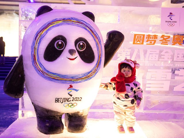 WUHAN, CHINA - DECEMBER 21: (CHINA OUT) Local residents pose and take pictures with 2022 Winter Olympics mascots during an ice and snow art festival in Wuhan Optical Valley Tennis Center on December 21, 2021 in Wuhan, Hubei Province, China. With just over a month before the Beijing Winter Olympics, the launching ceremony of the 8th National Public Ice and Snow Season was held in Wuhan and the central Chinese region for the first time. As a vital part of the largest ice and snow event in China before the Beijing Winter Olympics, an ice and snow art festival covering an area of nearly 1,000 square meters kicked off in Wuhan on Tuesday. A temporary indoor ice and snow sculpture exhibition, made by 400 tons of ice and 50 tons of snow, was open to the public and will last until January 3, 2022. Besides the sculptures of Wuhan’s landmarks, Winter Olympics mascots and cute animals, entertainment facilities such as ice slides and bumper cars on ice bring citizens in southern part of China even closer to experience the joy of ice and snow. (Photo by Getty Images)