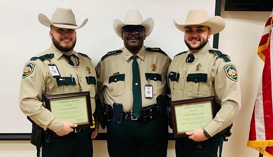 Polk County Sheriff Byron Lyons (center) presents the department's Lifesaving Award to Corporal Roper Ellison (R) and Deputy Darin Brooks (L) after they successfully removed a wheelchair bound man from a burning home near Livingston, Texas. (Photo: Polk County Sheriff's Office) 