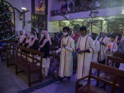 Indian Catholic altar boys, wearing face masks as a precaution against the COVID-19, walk