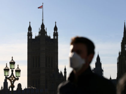 A pedestrian wearing a face mask or covering due to the COVID-19 pandemic, walks across Westminster Bridge, near the houses of Parliament in central London on January 25, 2021. - Over 30 new coronavirus vaccination centres were set to open around England this week as Britain's largest ever innoculation programme …