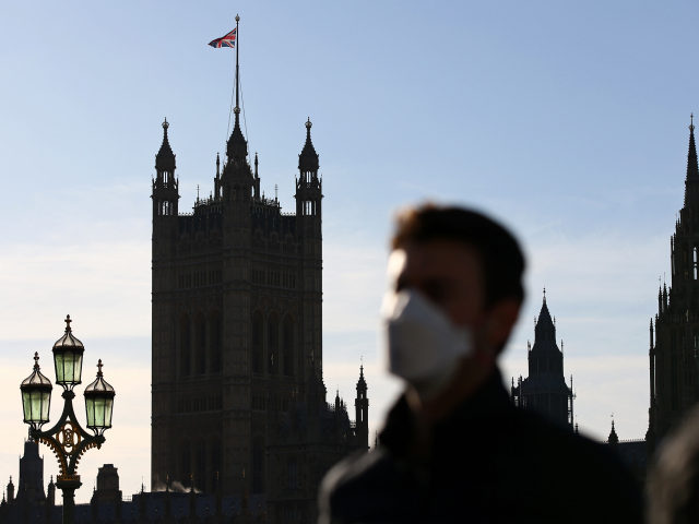 A pedestrian wearing a face mask or covering due to the COVID-19 pandemic, walks across We