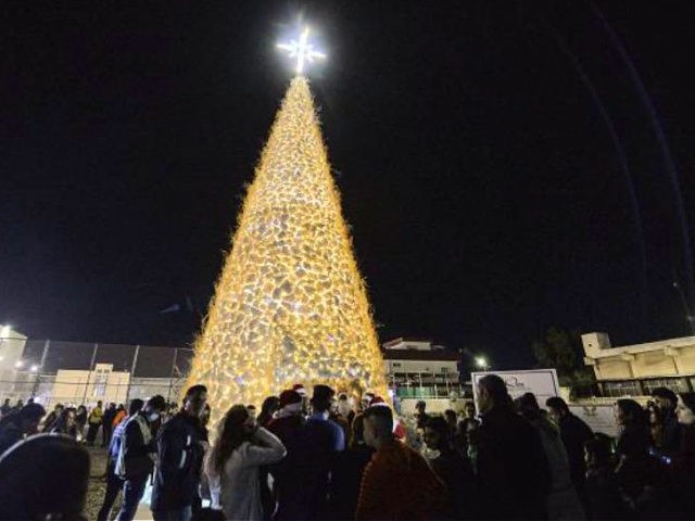 People gather by the giant hollow Christmas tree set up in Iraq's predominantly Christian