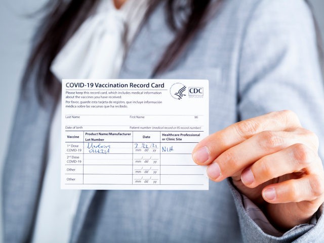 A woman showing a vaccination record card (Stock Photo via Getty)