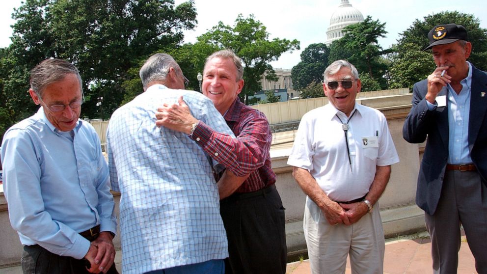 Edward Shames, center, hugs Ed McClung, center left, both members of the World War II Army Company E of the 506th Regiment of the 101st Airborne, with veterans Jack Foley, left, Joe Lesniewski, right, and Shifty Powers, far right, at the Library of Congress in Washington, on July 16, 2003. Shames, who was the last surviving officer of “Easy Company,” which inspired the HBO miniseries and book “Band of Brothers,” has died at age 99. An obituary posted by the Holomon-Brown Funeral Home & Crematory said Shames, of Norfolk, Va., died peacefully at his home on Friday, Dec. 3, 2021. (AP Photo/Gerald Herbert, File)