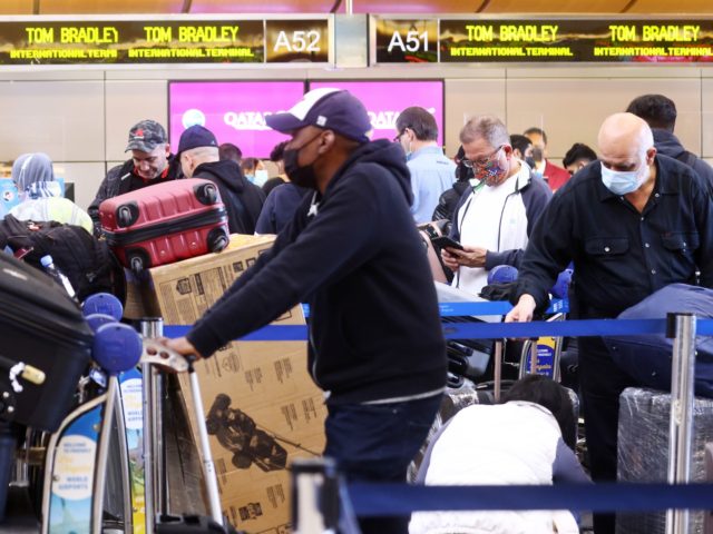 LOS ANGELES, CALIFORNIA - DECEMBER 21: People wait on line to check in for their flights in the international terminal at Los Angeles International Airport (LAX) amid a surge in omicron variant cases on December 21, 2021 in Los Angeles, California. AAA estimates that over 109 million Americans will be …