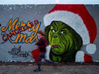 TOPSHOT - A mural painting by graffiti artist Eme Freethinker features a likeness of US author Dr Seuss' Grinch character with a "cancelled" stamp across a Merry Christmas sign, in Berlin on December 27, 2020. (Photo by John MACDOUGALL / AFP) / RESTRICTED TO EDITORIAL USE - MANDATORY MENTION OF …