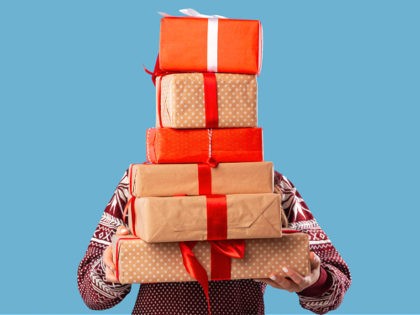 Young woman holding stack of gift boxes over blue studio background. Unrecognizable millennial lady with pile of Christmas or New Year presents. Shopping for winter holidays concept