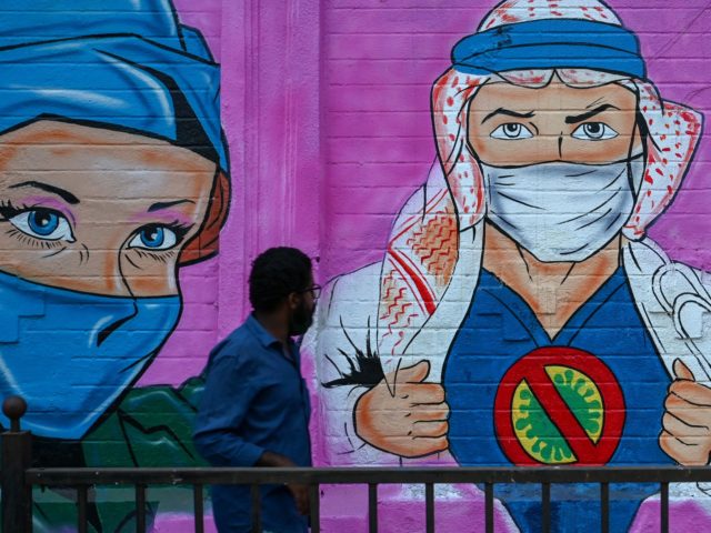 TOPSHOT - A pedestrian walks past a wall mural depicting health workers to spread awareness about the Covid-19 coronavirus in Mumbai on November 30, 2021. (Photo by Punit PARANJPE / AFP) (Photo by PUNIT PARANJPE/AFP via Getty Images)