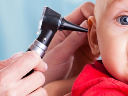 Pediatrician using otoscope to examine baby's ear