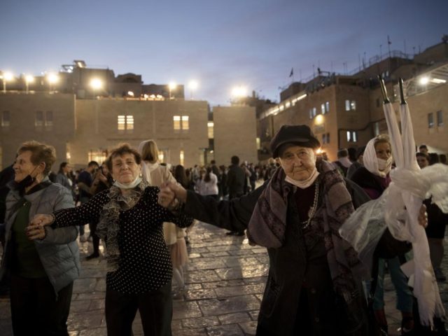 Holocaust survivors dance during a Hanukkah menorah lighting ceremony at the Western Wall, in the Old City of Jerusalem, Tuesday, Nov. 30, 2021. Holocaust survivors marked the third night of Hanukkah on Tuesday with a menorah-lighting ceremony at Jerusalem's Western Wall that paid tribute to them and the 6 million …