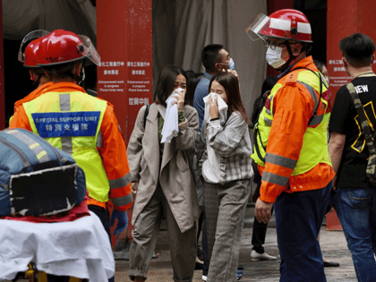 People walk out from the World Trade Centre where is located in the city's popular Causeway Bay shopping district of Hong Kong, Wednesday, Dec. 15, 2021. Dozens of people are trapped on the rooftop of the Hong Kong skyscraper after a major fire broke out Wednesday, as firefighters rushed to …
