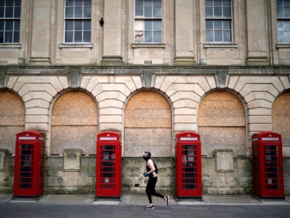 BLACKPOOL, ENGLAND - APRIL 02: A man wearing a mask jogs past red phone boxes in Blackpool town centre as people and businesses observe the pandemic lockdown and stay home on April 02, 2020 in Blackpool, England. Traditional seaside towns across Britain will be closed over the Easter Holiday weekend, …