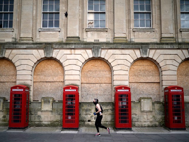 BLACKPOOL, ENGLAND - APRIL 02: A man wearing a mask jogs past red phone boxes in Blackpool