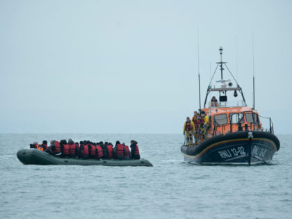 TOPSHOT - Migrants are helped by RNLI (Royal National Lifeboat Institution) lifeboat before being taken to a beach in Dungeness, on the south-east coast of England, on November 24, 2021, after crossing the English Channel. - The past three years have seen a significant rise in attempted Channel crossings by …