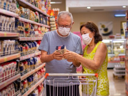 A senior couple shopping at the market with protective masks