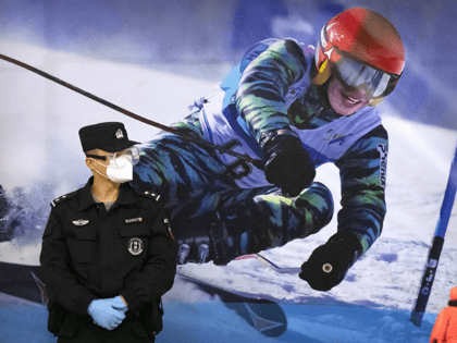 A police officer wearing a face mask and goggles to protect against COVID-19, stands near a poster of a skier on the wall at a train station in Zhangjiakou in northern China's Hebei Province, Friday, Nov. 26, 2021. China is threatening to take “firm countermeasures" if the U.S. proceeds with …