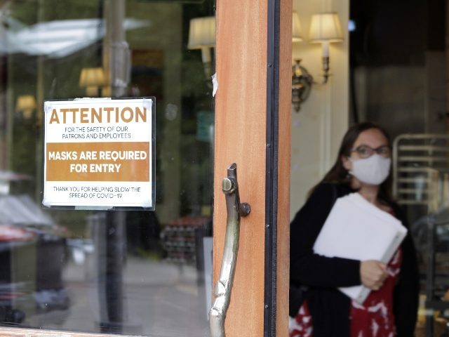 A sign reminds customers to wear their masks at a bakery in Lake Oswego, Ore., on Friday, May 21, 2021. As the federal government and many states ease rules around mask-wearing and business occupancy, some blue states like Oregon and Washington are still holding on to some longtime coronavirus restrictions. …