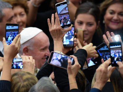 People take photos of Pope Francis (Rear L) with their smartphone as he arrives for an aud