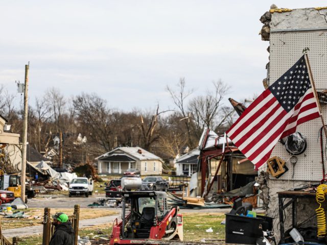 A US national flag waves among tornado damage after extreme weather hit the region in Bowl