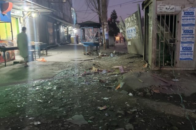 An Afghan man walks past shattered glass near the site of an explosion in Dasht-e-Barchi d