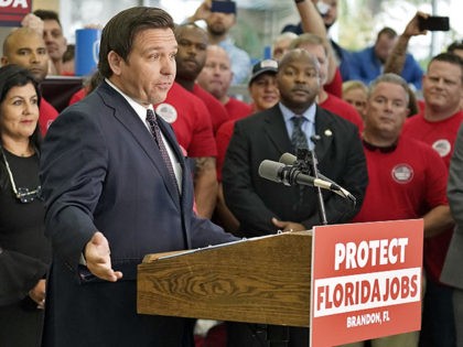 As supporter holds up a Brandon, Florida sign as Florida Gov. Ron DeSantis, center, speaks to members of the media before a bill signing Thursday, Nov. 18, 2021, in Brandon, Fla. Gov. DeSantis has embraced “Let’s go Brandon.” The Republican governor's campaign said they picked the small Tampa suburb of …