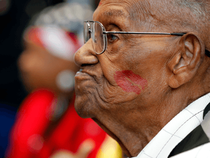 In this Sept. 12, 2019 file photo, World War II veteran Lawrence Brooks sports a lipstick kiss on his cheek, planted by a member of the singing group Victory Belles, as he celebrates his 110th birthday at the National World War II Museum in New Orleans. (AP Photo/Gerald Herbert, File)