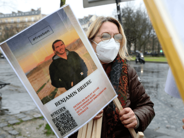 A woman holds a photo of Benjamin Briere during a rally in Paris, France, Saturday, Jan. 8, 2022. The French tourist jailed in Iran since last year who has begun a hunger strike to protest against mistreatment in prison, according to his sister and his lawyer. Briere, 36, was arrested …