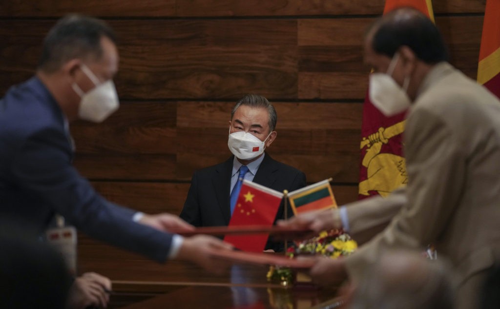 Chinese Foreign Minister Wang Yi, center, watches as bilateral agreements are signed and exchanged between officials of two countries in Colombo, Sri Lanka, Sunday, Jan. 9, 2022. (AP Photo/Eranga Jayawardena)
