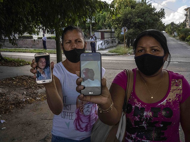 Servilia Pedroso, right, mother of 18-year-old student Eloy Barbaro Cardoso, and Yaquelin Cruz mother of Dariel Cruz, show the photos of their who were arrested during the July 11 protests, in front of the court building where they are being tried in Havana, Cuba, Tuesday, Jan. 11, 2022. Six months …