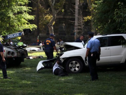 Investigators examine a heavily damaged SUV before it is towed from the scene of a fatal a