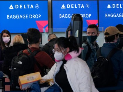 In this Dec. 22, 2020 file photo, people wait in line at a Delta Air Lines gate at San Fra