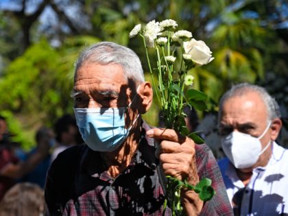 A man holds white flowers during the commemoration of the 40th anniversary of a massacre in El Mozote, 200 km east of San Salvador, on December 11, 2021. - Relatives of the victims at El Mozote are demanding justice against the impunity of 40 years in which the largest massacre …