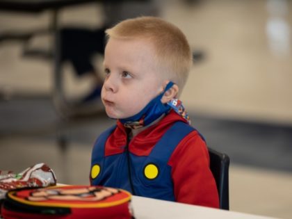 LOUISVILLE, KY - MARCH 17: A child with his mask lowered eats lunch at socially distanced tables in the cafeteria of Medora Elementary School on March 17, 2021, in Louisville, Kentucky. Today marks the reopening of Jefferson County Public Schools for in-person learning with new COVID-19 procedures in place.